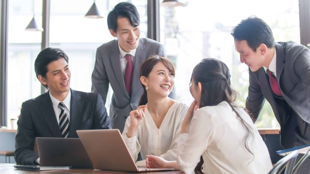 ノートパソコンを囲んで打ち合わせをするビジネスパーソン